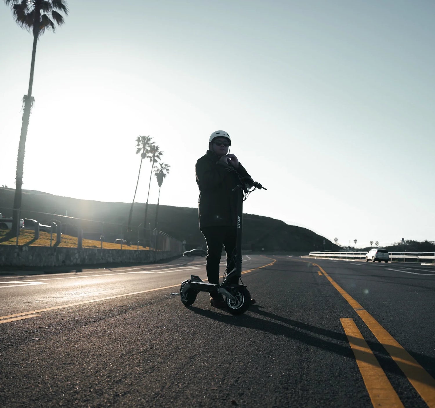 Apollo E-scooter riding on the road while driver is properly equipped with helmet.