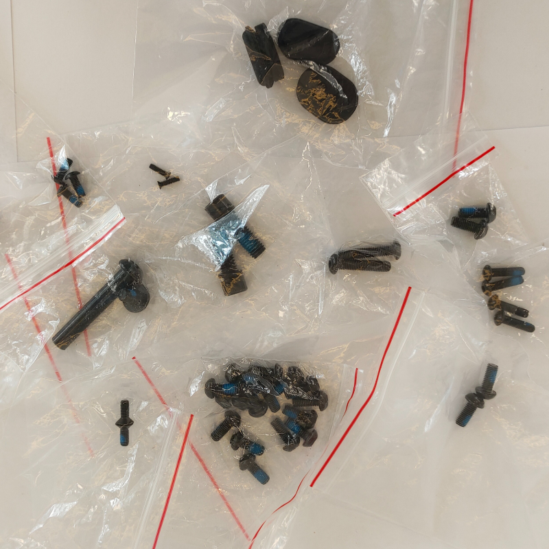 Assorted small mechanical parts in clear plastic bags on a white surface
