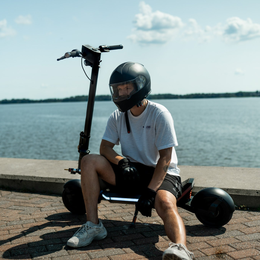 Person sitting on an Apollo Phantom electric scooter by a body of water