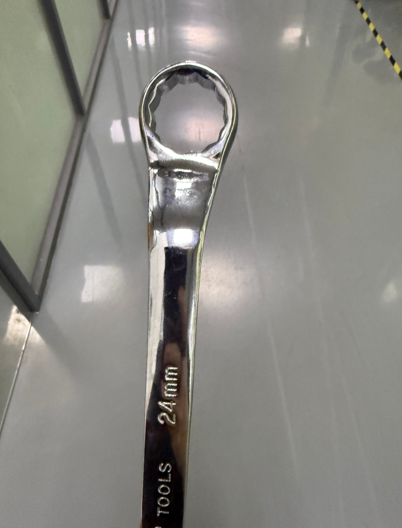Metal wrench with measurement '24 mm' on a reflective surface