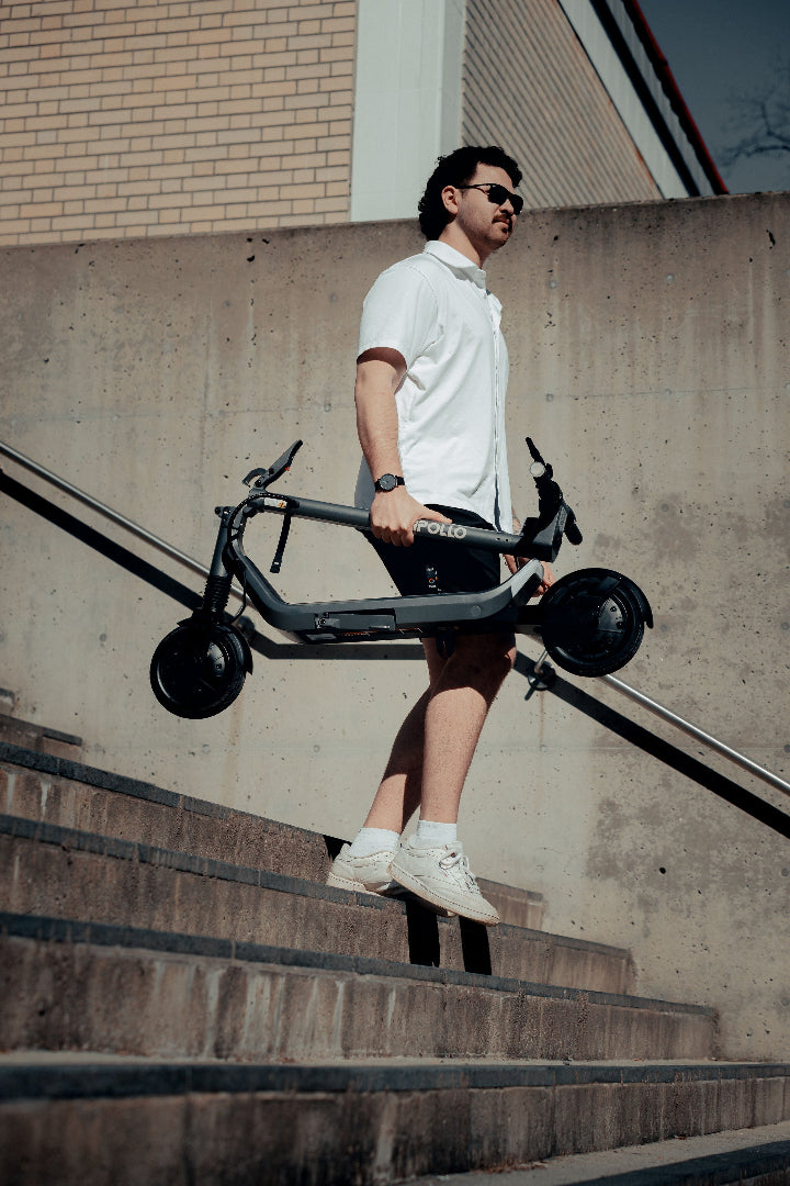 Apollo GO Scooter being carried by a man down the stairs