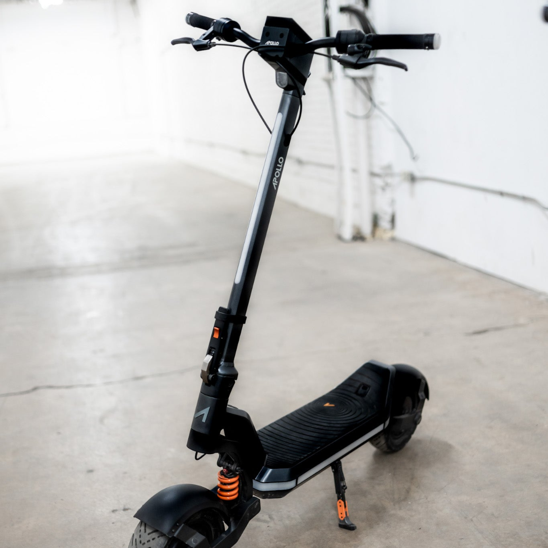 Black electric scooter on a concrete floor with a white wall background